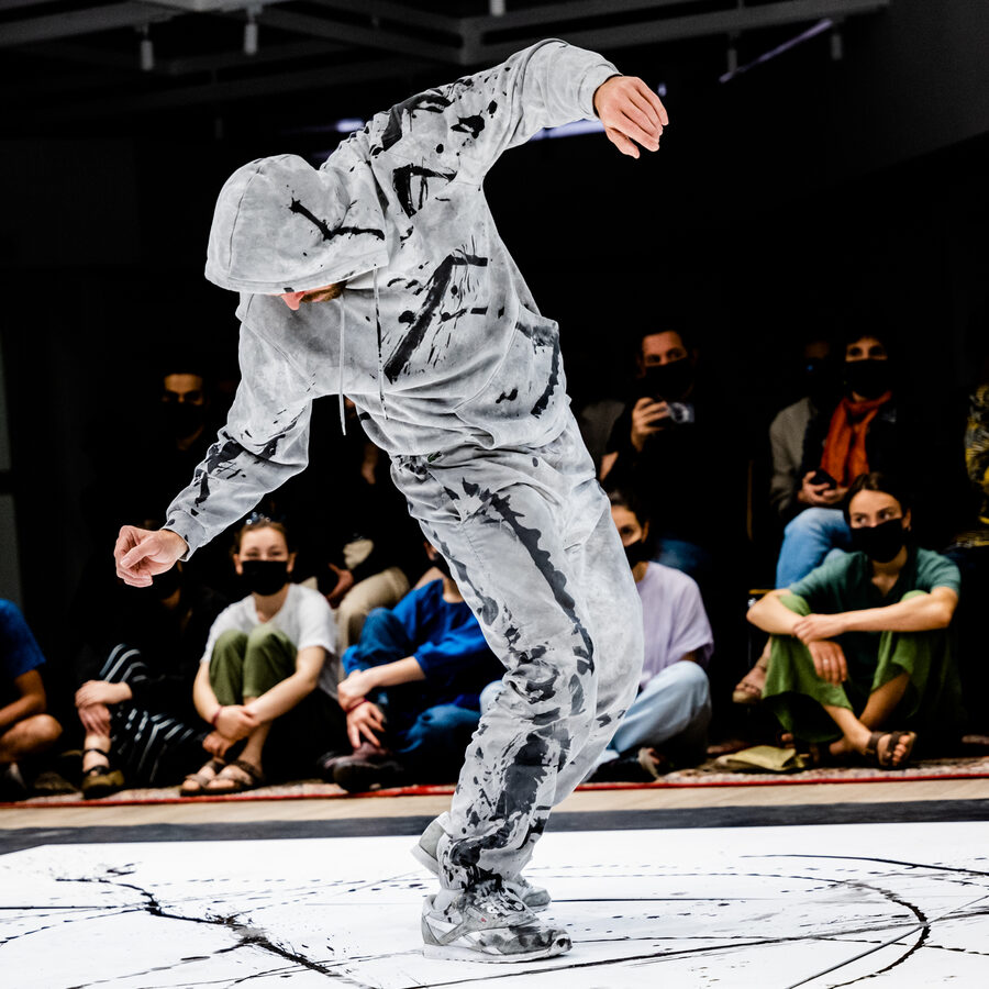Dancer mid-spin on an ink-marked canvas during Shared Canvas