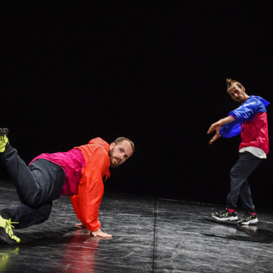 Two dancers on a dark stage floor during Signature Snippets